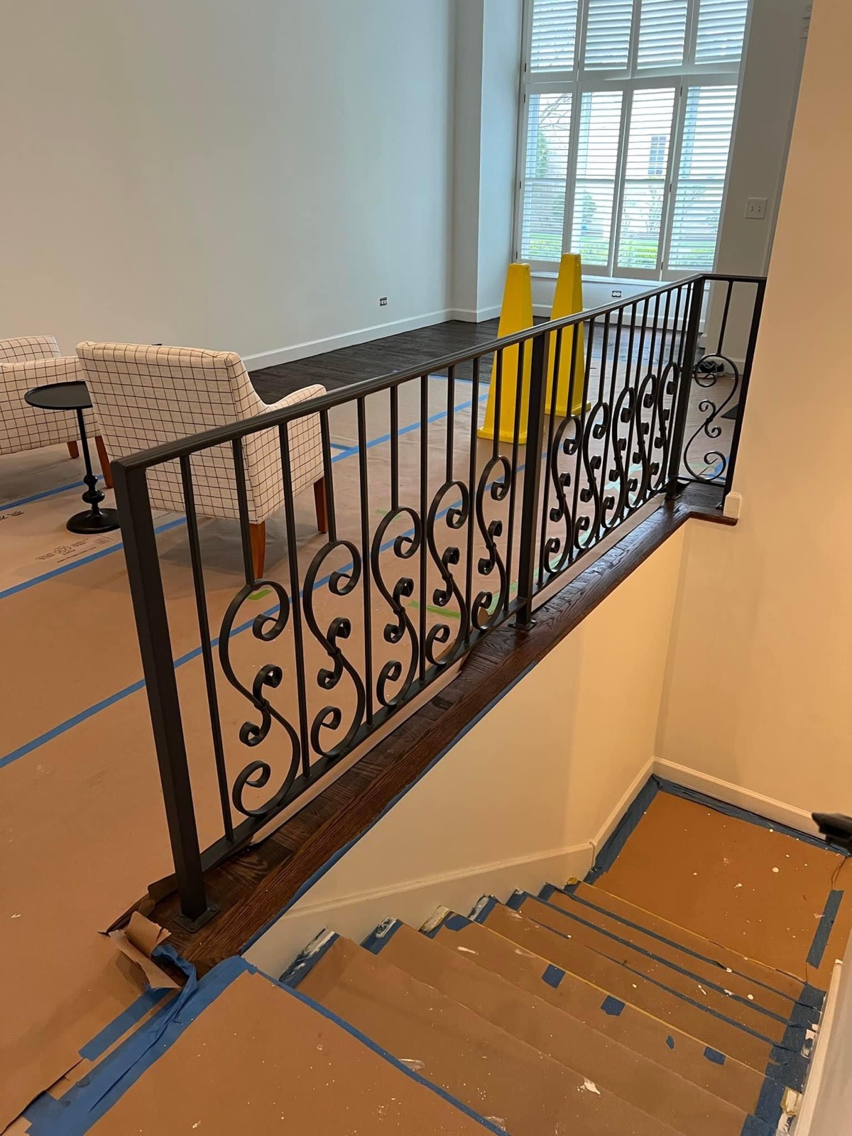Interior ornamental iron railing installed along an open stairwell inside a finished home.