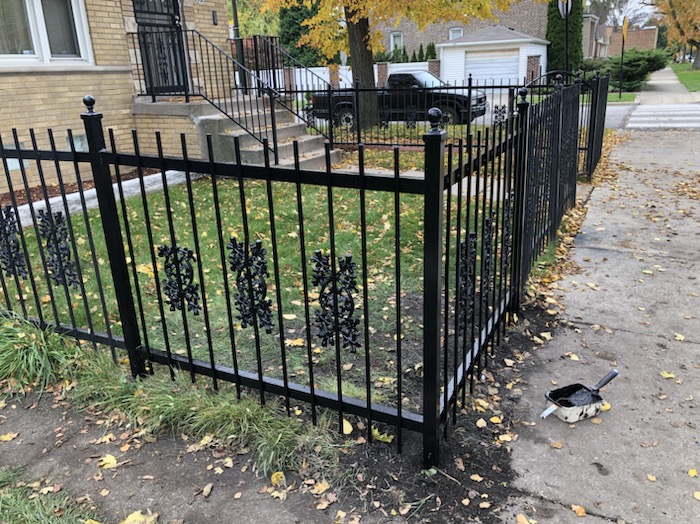 Finished ornamental black steel fence corner installed around a front yard.
