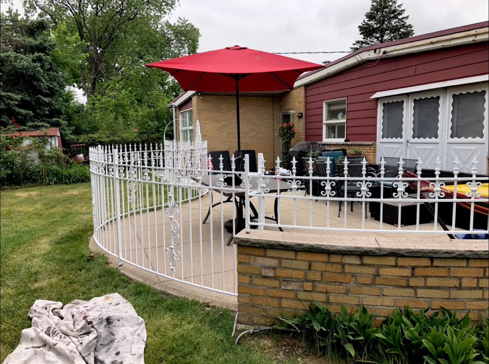 White ornamental metal fence wrapping a residential yard and patio area.