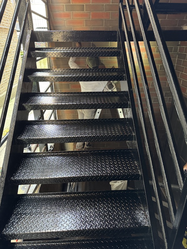 Finished black steel stair treads and landing after repair and coating work.